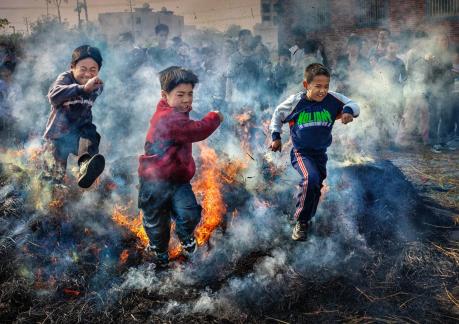 Three children jumping over fire